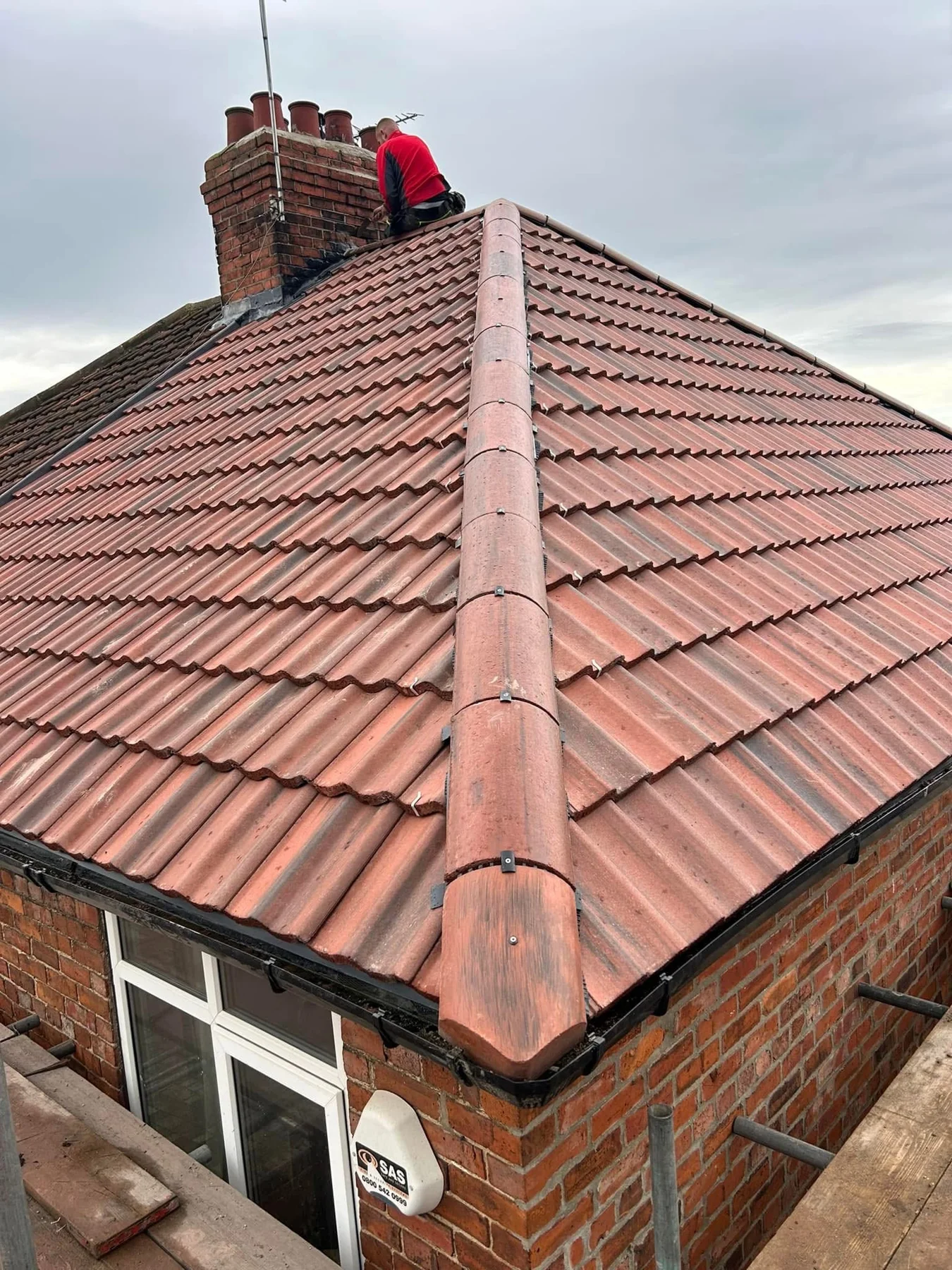 Renewed red tiled roof and hip ridge beside a chimney